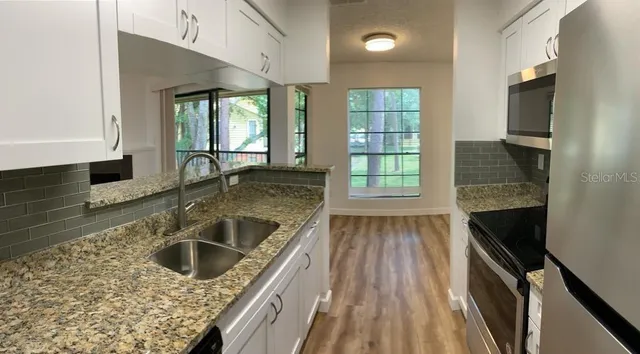 a kitchen with granite countertop a stove sink and microwave