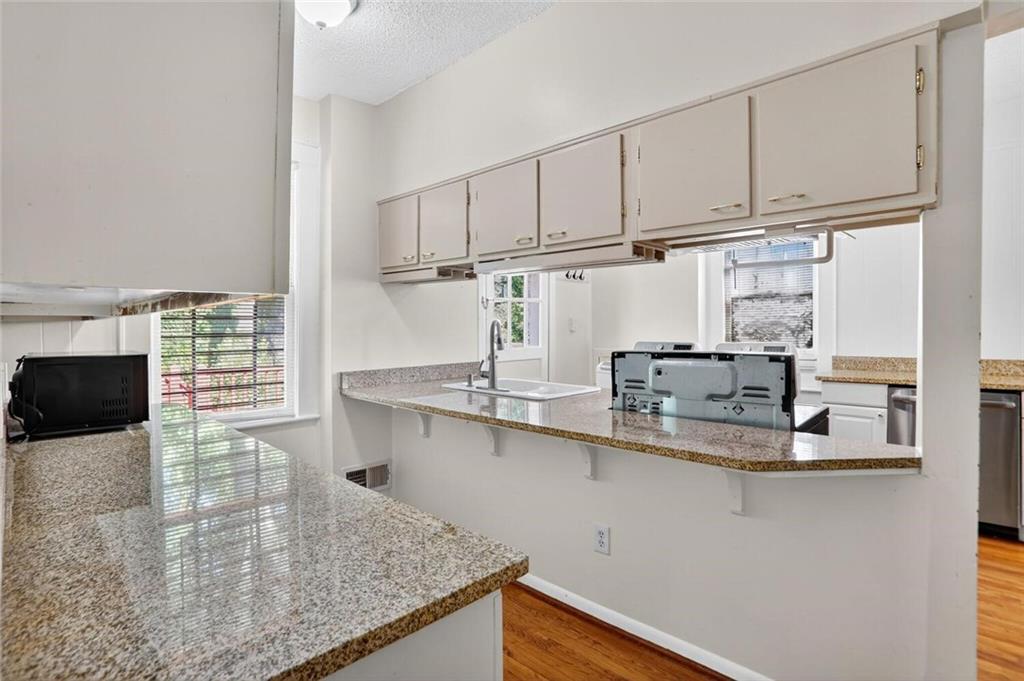 1497 North Morningside Drive Northeast Atlanta, GA 30306 - Photo 10 of 36 a kitchen with stainless steel appliances granite countertop a sink a stove and white cabinets