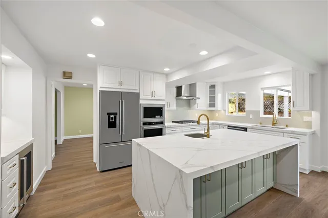 a kitchen with stainless steel appliances a kitchen island sink refrigerator and cabinets