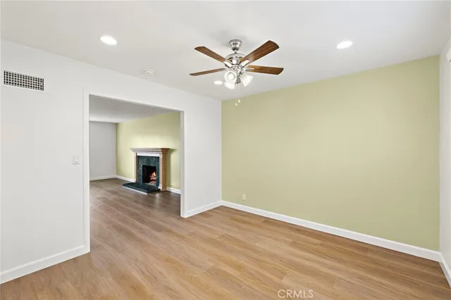 an empty room with wooden floor a ceiling fan and windows