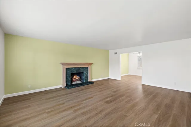 a view of an empty room with wooden floor fire place
