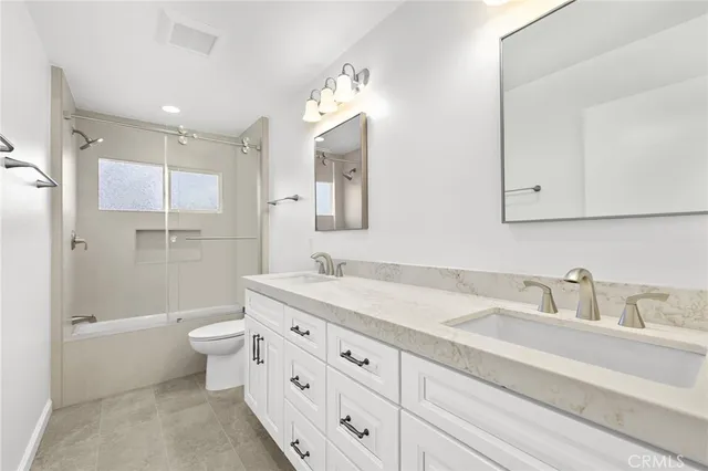 a bathroom with a granite countertop sink a toilet and shower