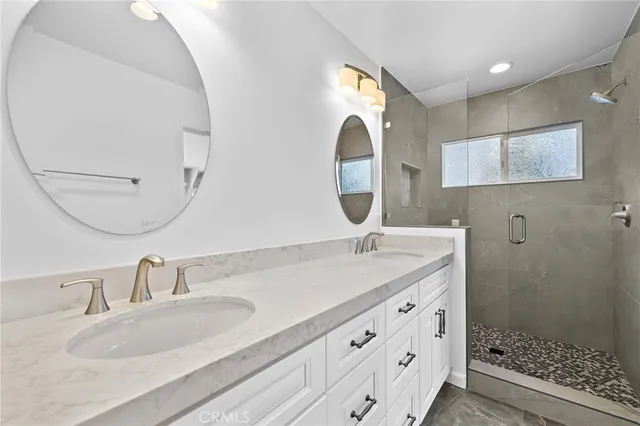a bathroom with a double vanity sink mirror and shower