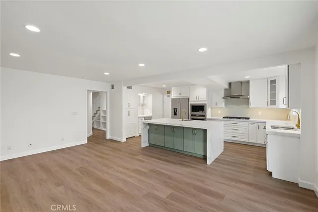 a large white kitchen with stainless steel appliances granite countertop a stove and a refrigerator