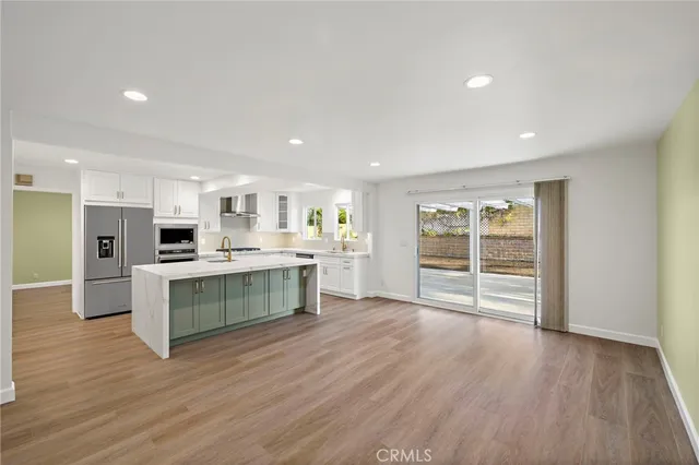 a large white kitchen with wooden floors and view living room