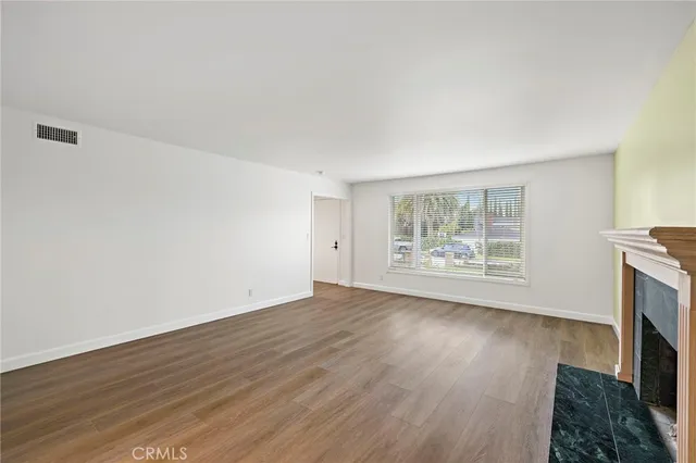 an empty room with wooden floor and fireplace