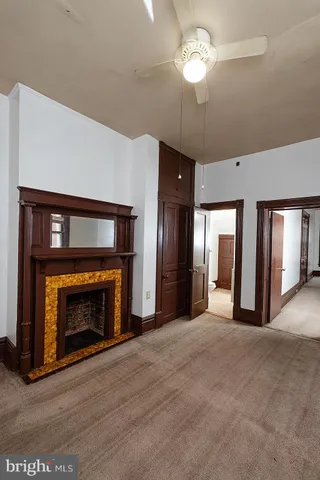 a view of an empty room with chandelier fan and fire place