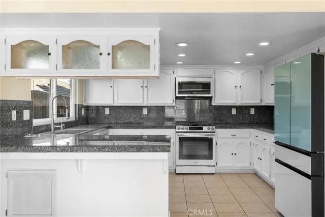 a kitchen with stainless steel appliances granite countertop a stove a sink and a microwave