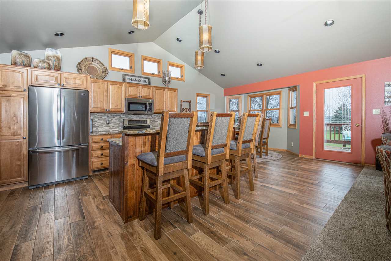 12410 Beaverton Road Poplar Grove, IL 61065 - Photo 11 of 37 a kitchen with stainless steel appliances granite countertop a refrigerator a stove top oven a dining table and chairs with wooden floor