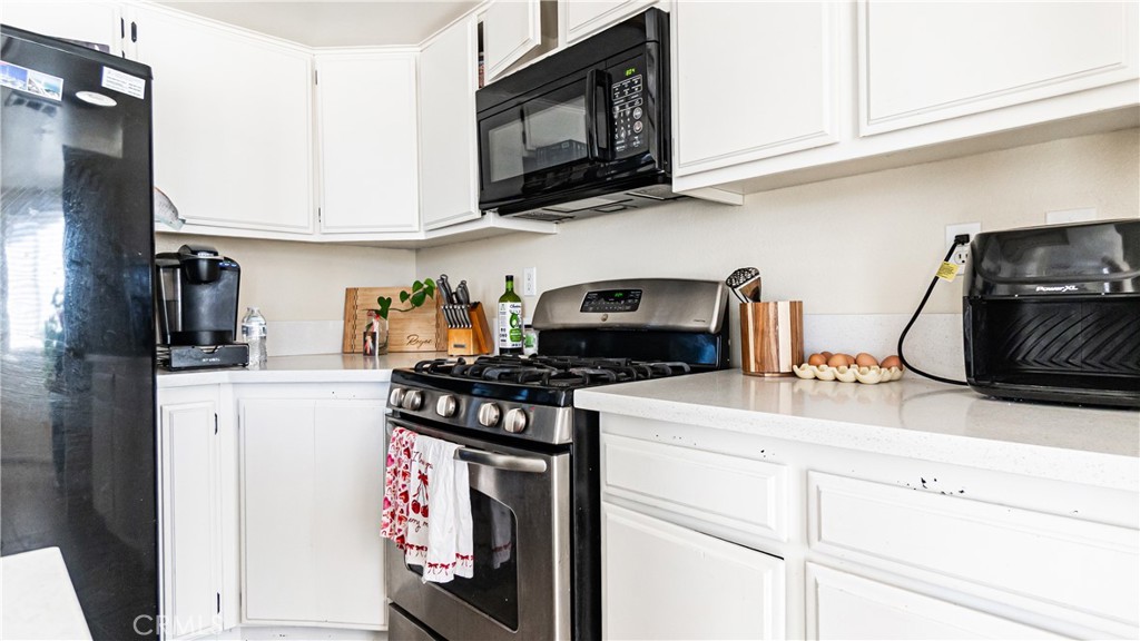 22993 Eyota Road Apple Valley, CA 92308 - Photo 14 of 38 a kitchen with stainless steel appliances granite countertop a stove a microwave and cabinets