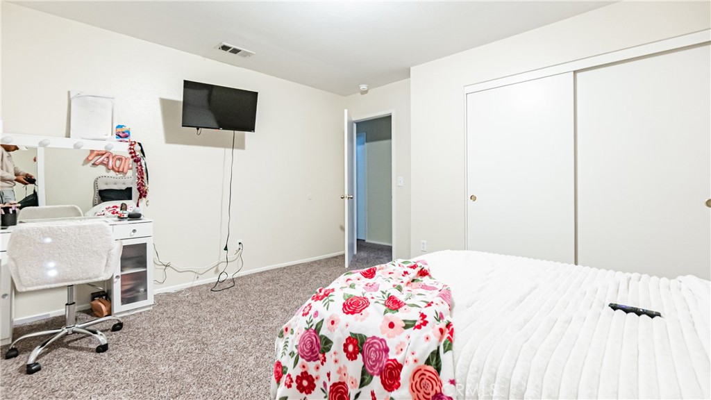 22993 Eyota Road Apple Valley, CA 92308 - Photo 22 of 38 a bedroom with a bed and a flat screen tv