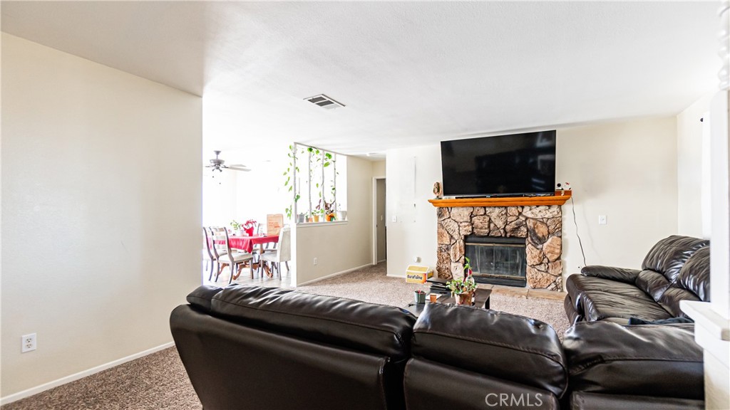 22993 Eyota Road Apple Valley, CA 92308 - Photo 5 of 38 a living room with furniture a flat screen tv and a fireplace