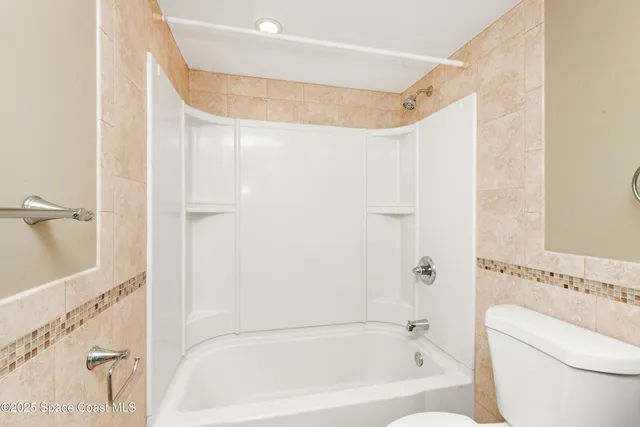 a bathroom with a bathtub shower and toilet
