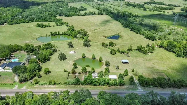 an aerial view of residential houses with outdoor space and trees all around