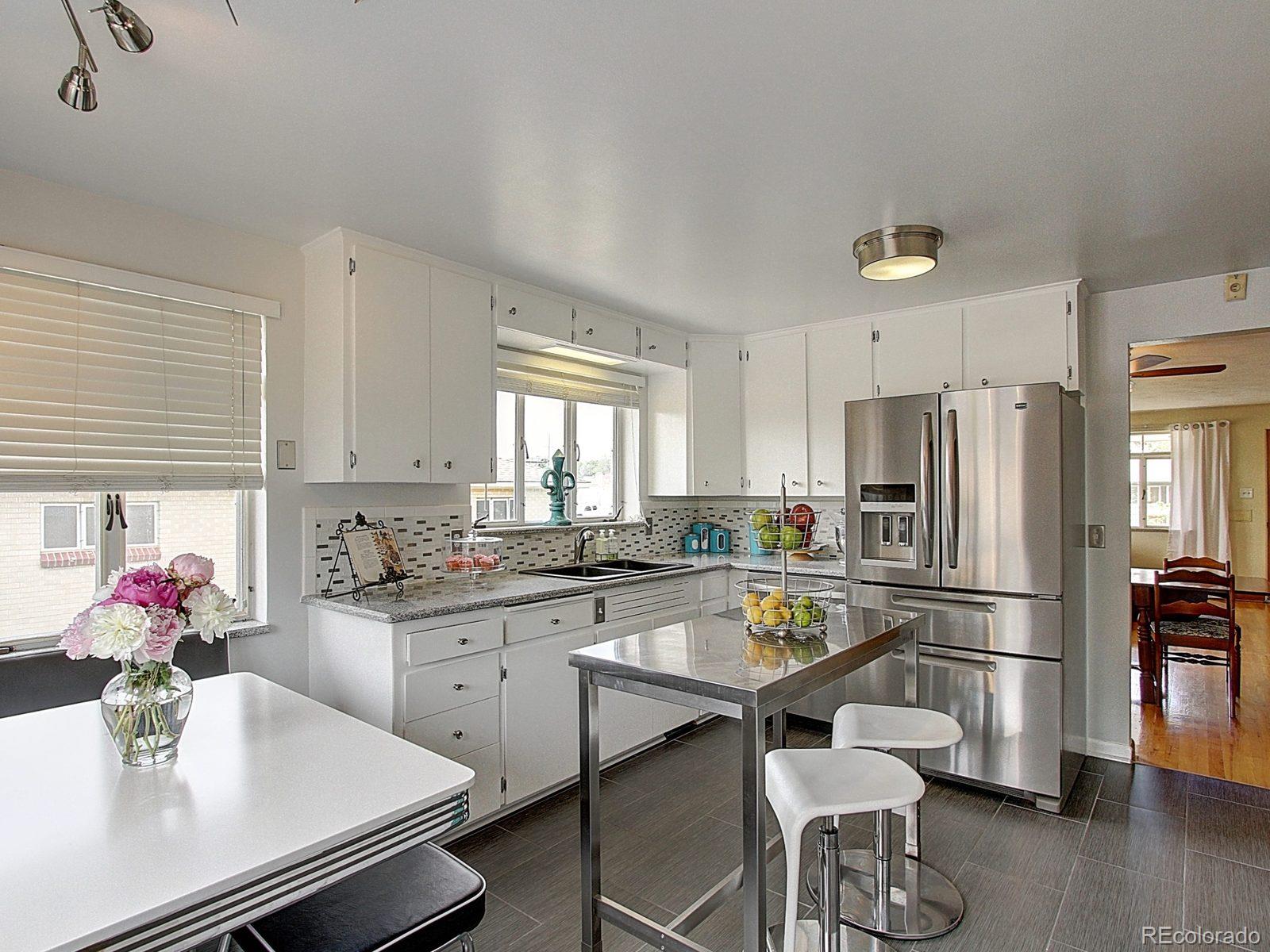 3840 Pierce Street Wheat Ridge, CO 80033 - Photo 11 of 32 a kitchen with a dining table chairs refrigerator and microwave