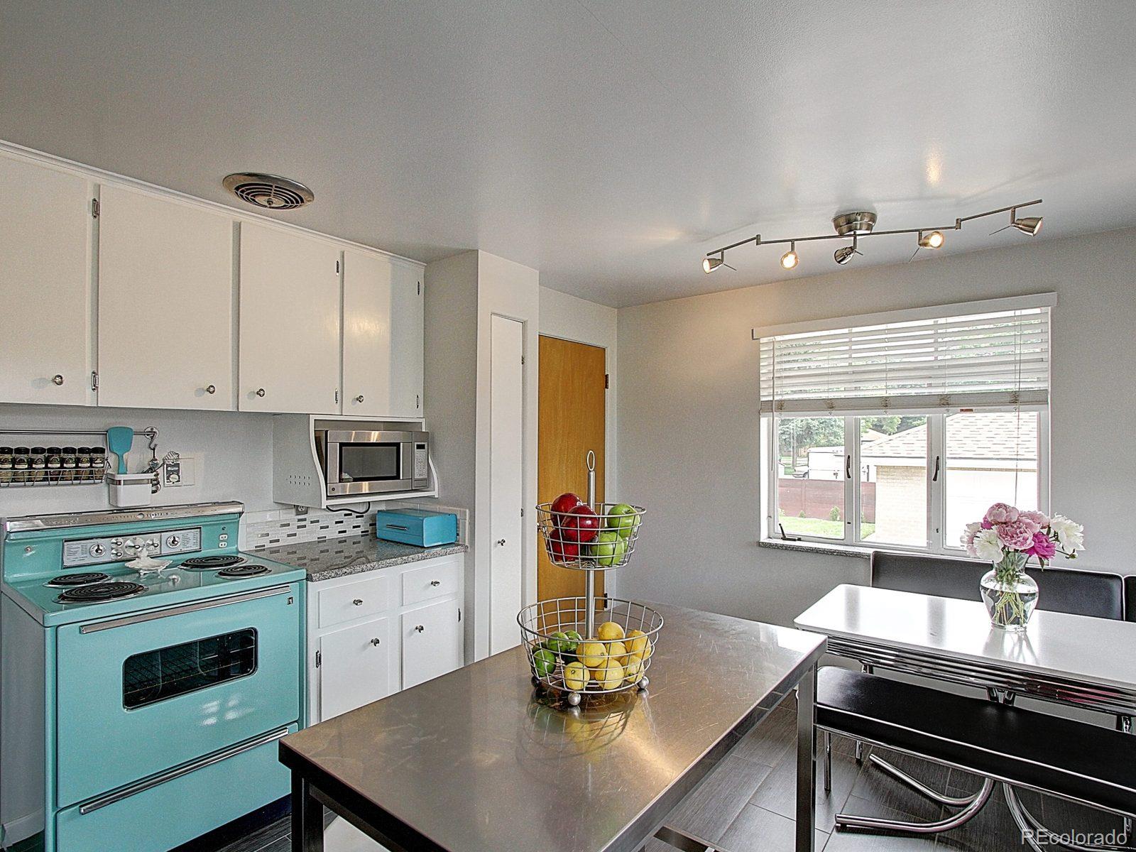 3840 Pierce Street Wheat Ridge, CO 80033 - Photo 13 of 32 a kitchen with kitchen island granite countertop a sink cabinets appliances and a window