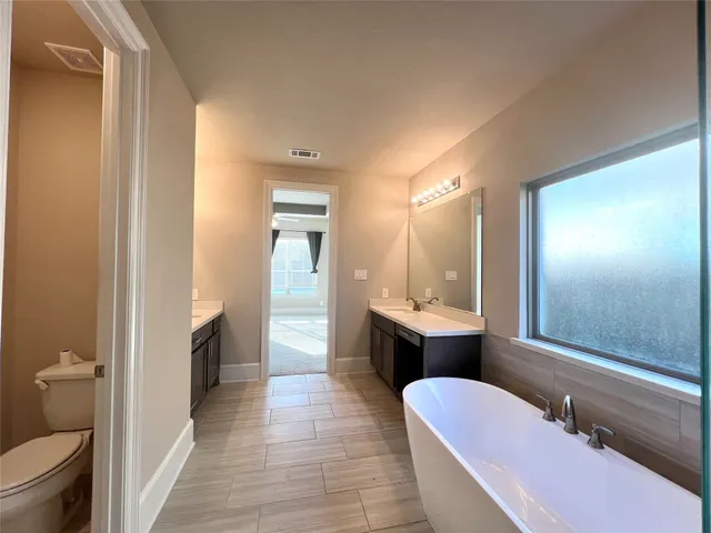 a bathroom with a bathtub shower sink mirror and toilet