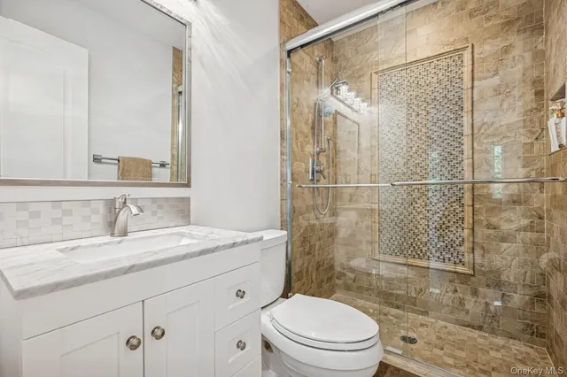 a bathroom with a granite countertop sink toilet a mirror and shower