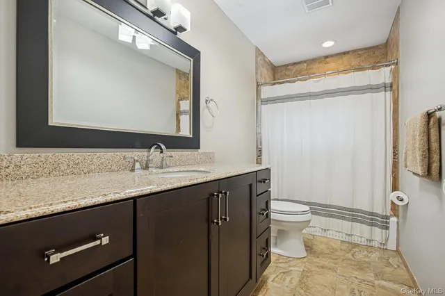 a bathroom with a granite countertop sink toilet and shower