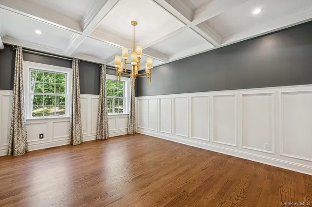 a view of an empty room with wooden floor fridge and a window