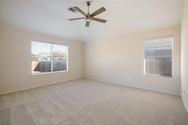 an empty room with windows and fan