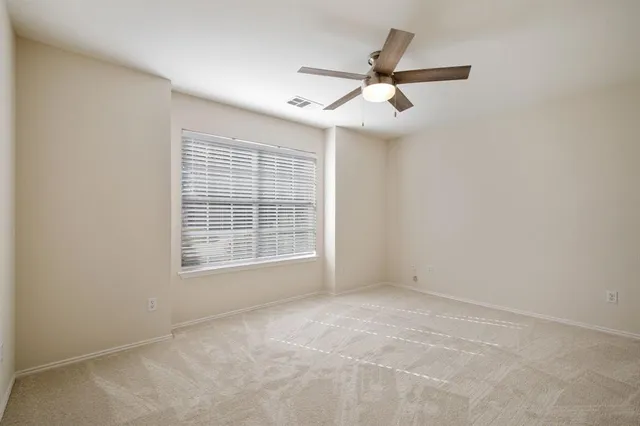 an empty room with chandelier fan and windows