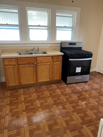 a kitchen with granite countertop a stove a sink and a window