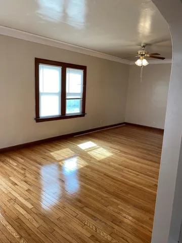 a view of empty room with wooden floor and fan