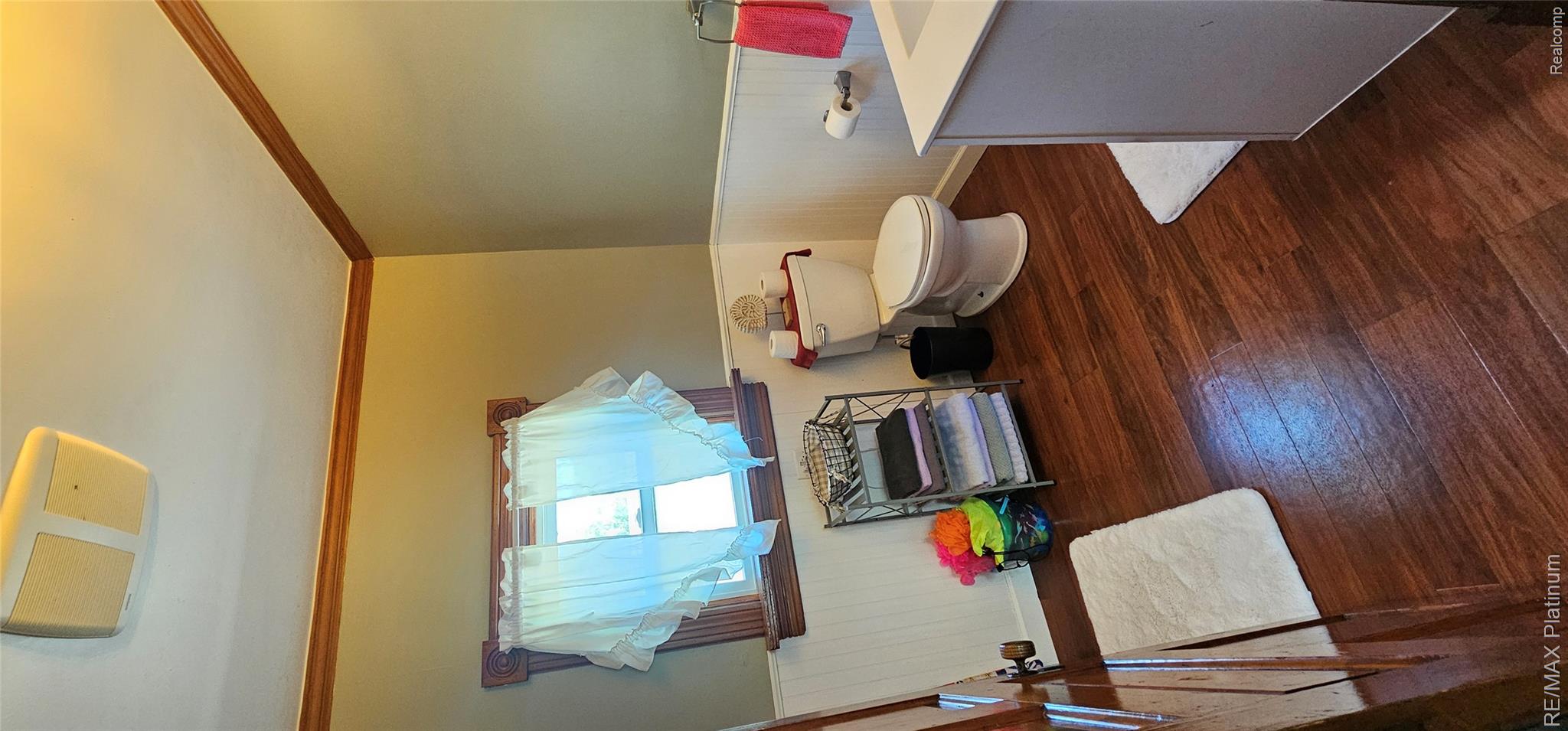 17140 Haggerty Road Belleville, MI 48111 - Photo 22 of 42 Bathroom featuring wood-finish flooring, beadboard wainscoting, a window with wood trim, and a built-in vanity with a white countertop