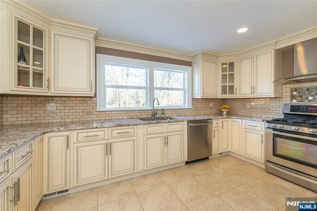 a kitchen with white cabinets appliances a sink and a window