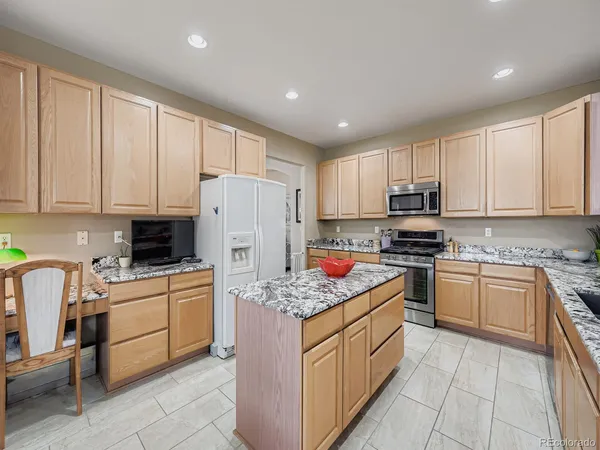 a kitchen with stainless steel appliances granite countertop a stove top oven a refrigerator a sink and white cabinets