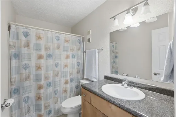 a bathroom with a granite countertop sink a toilet a mirror a shower and a sink