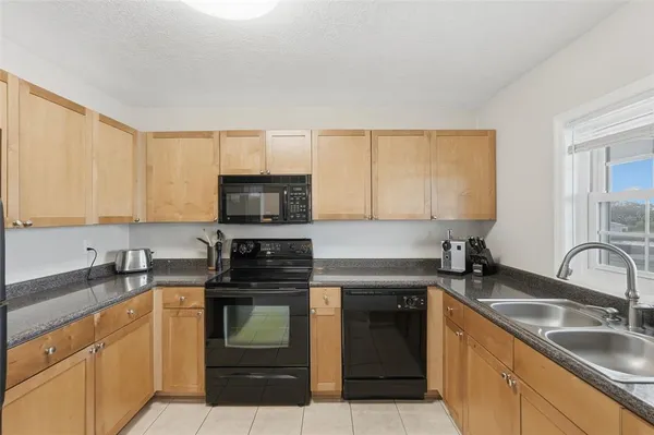 a kitchen with granite countertop a sink a stove and cabinets