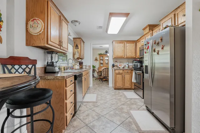 a kitchen with stainless steel appliances granite countertop a refrigerator a stove a sink and a dining table with wooden cabinet