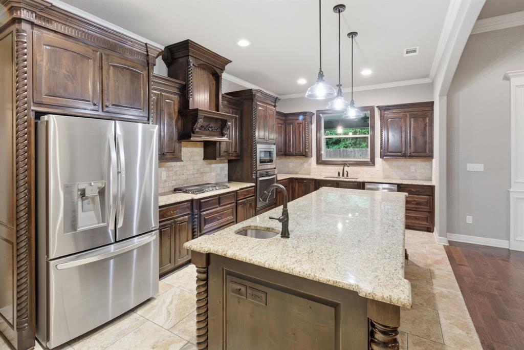 7765 Hickory Spring Lane Tyler, TX 75703 - Photo 18 of 38 Gourmet kitchen featuring a large central island with granite countertop, stainless steel appliances, dark wood cabinetry with decorative molding, and tile flooring