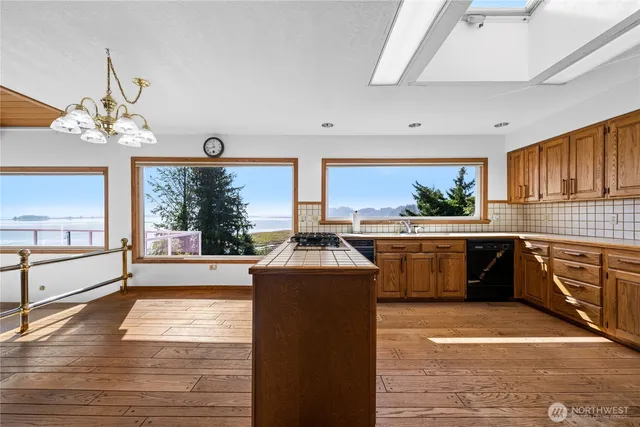 a kitchen with stainless steel appliances a stove a sink and white cabinets with wooden floor