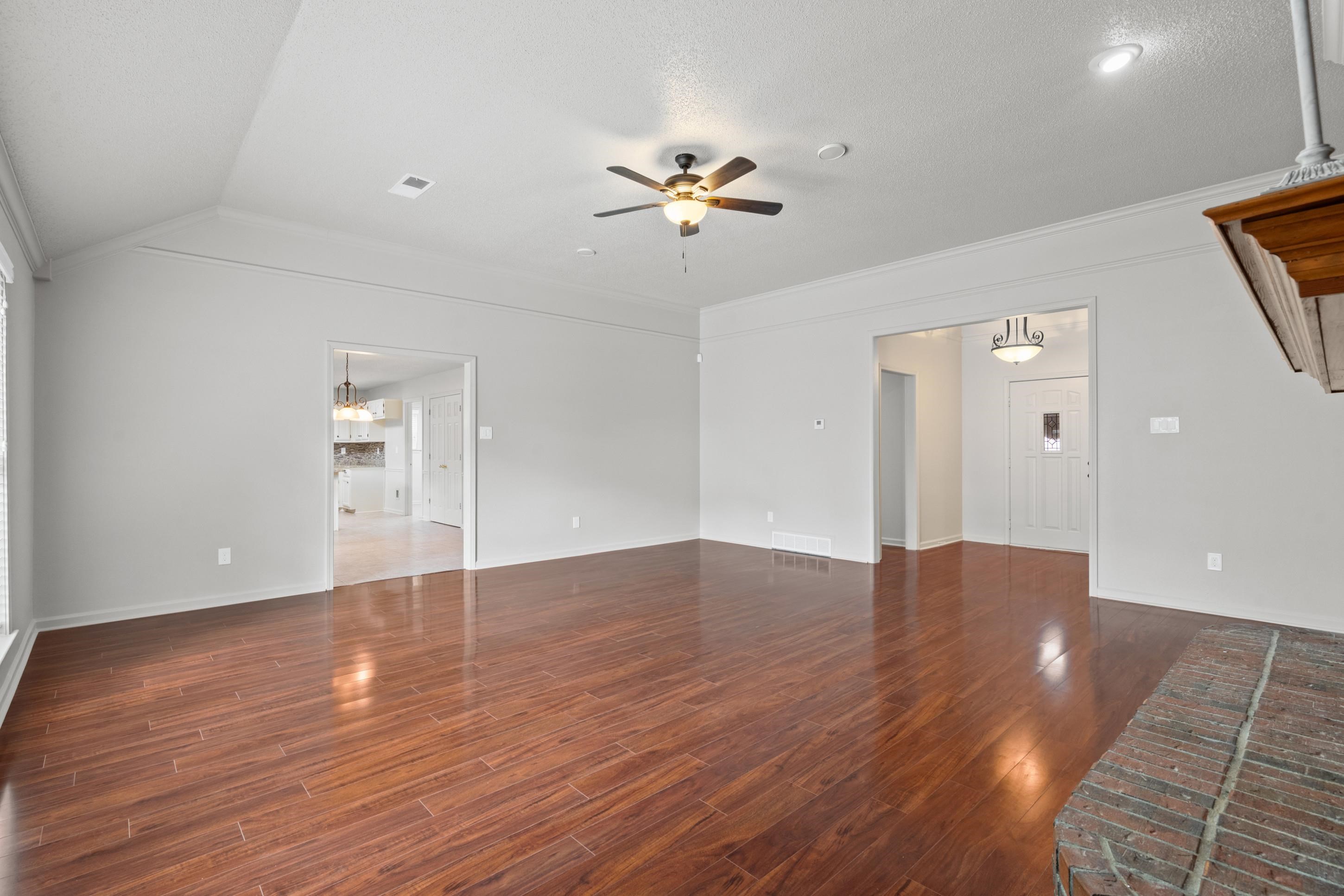 1301 Wolf Lair Drive Collierville, TN 38017 - Photo 11 of 32 Unfurnished living room with dark wood-style floors, ceiling fan, hanging lights, and crown molding