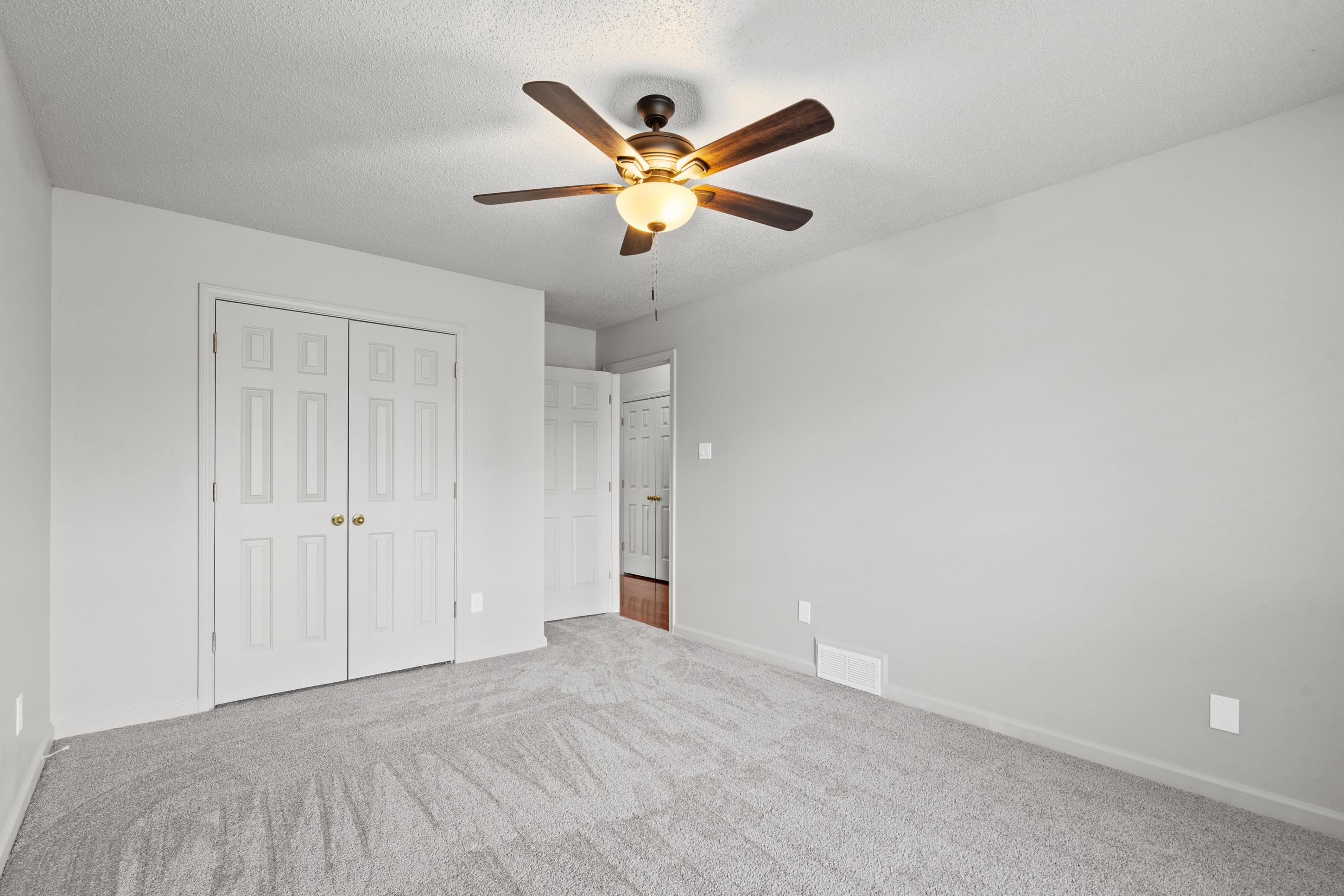 1301 Wolf Lair Drive Collierville, TN 38017 - Photo 19 of 32 Unfurnished bedroom featuring ceiling fan, a closet, light colored carpet, and a textured ceiling