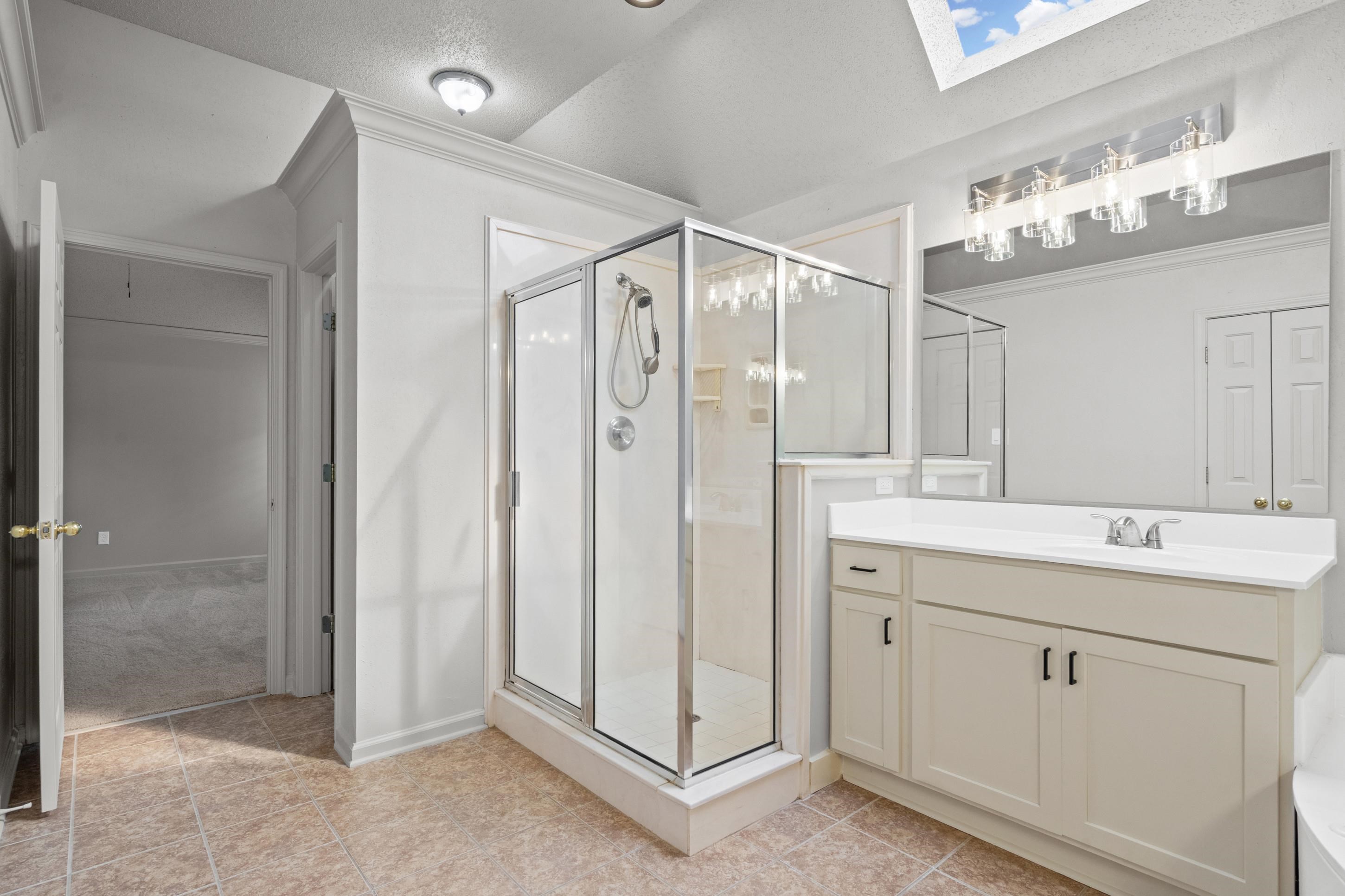1301 Wolf Lair Drive Collierville, TN 38017 - Photo 21 of 32 Bathroom with vanity, a stall shower, a skylight, crown molding, and a textured ceiling