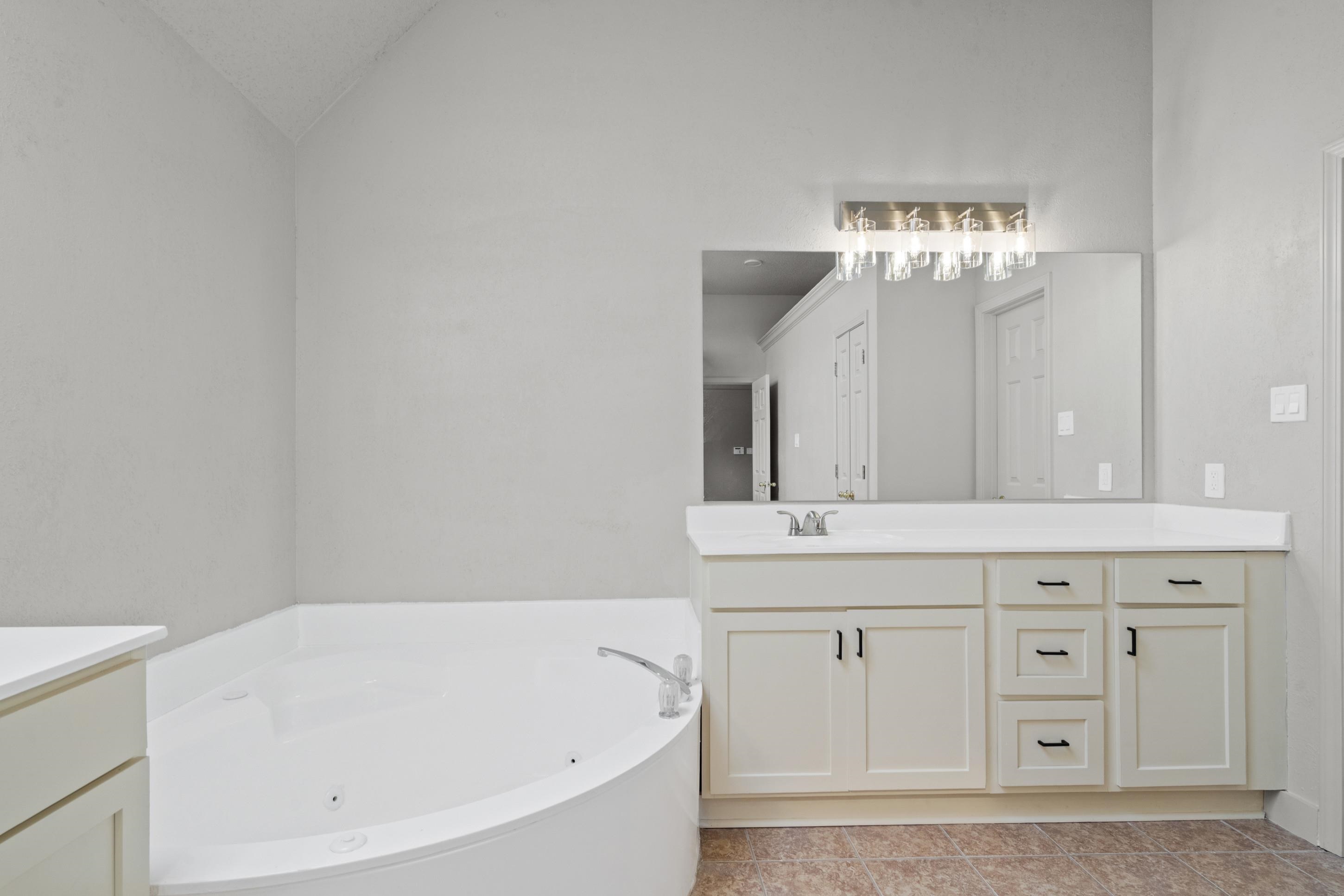 1301 Wolf Lair Drive Collierville, TN 38017 - Photo 22 of 32 Primary Bathroom with vanity, a whirlpool tub, lofted ceiling, skylight and light tile patterned flooring
