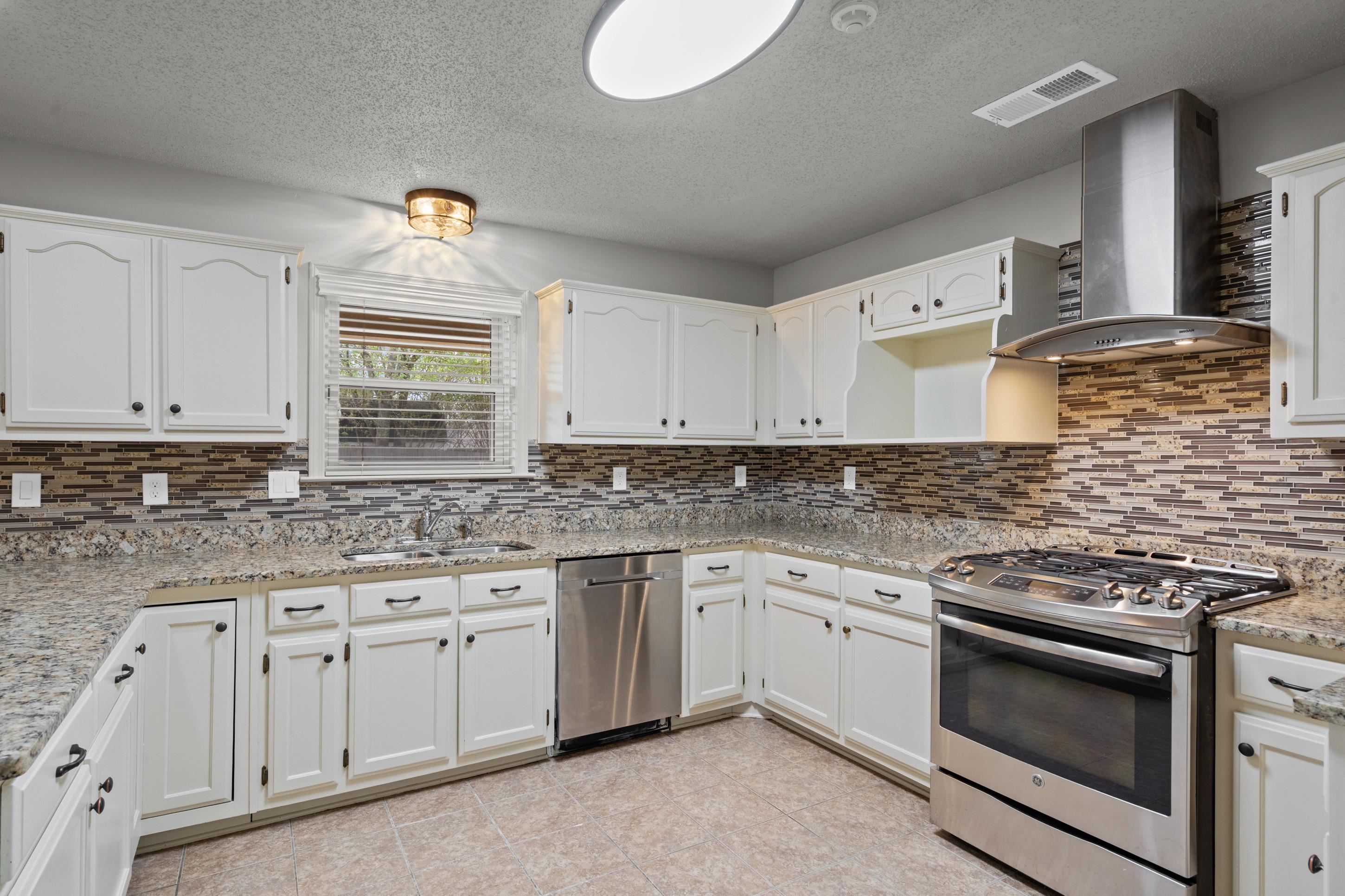 1301 Wolf Lair Drive Collierville, TN 38017 - Photo 5 of 32 Kitchen with stainless steel appliances, a textured ceiling, light stone counters, white cabinets, and light tile patterned floors