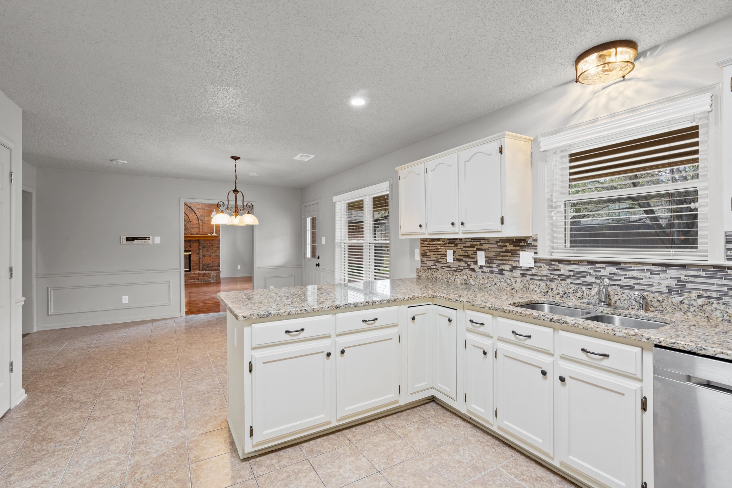 1301 Wolf Lair Drive Collierville, TN 38017 - Photo 6 of 32 Kitchen featuring dishwasher, light stone counters, hanging lights, white cabinets, and wainscoting