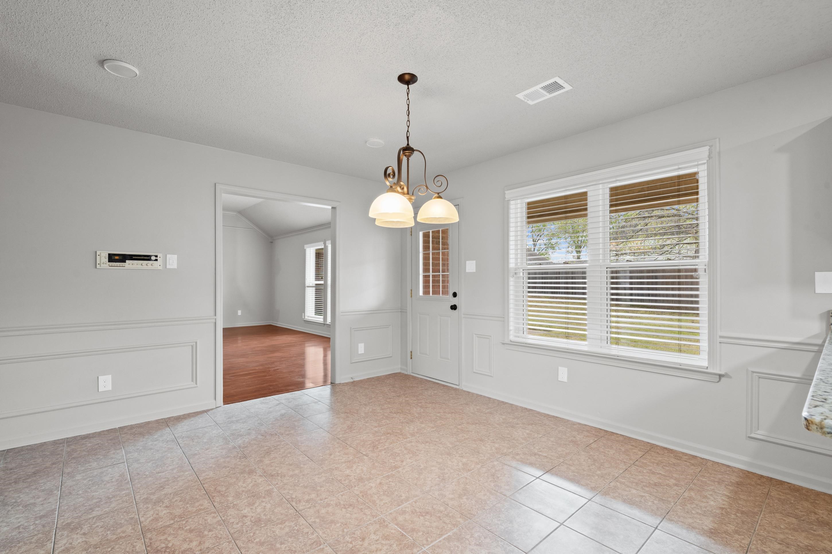 1301 Wolf Lair Drive Collierville, TN 38017 - Photo 7 of 32 Unfurnished dining area featuring a decorative wall, a textured ceiling, a wainscoted wall, and light tile patterned floors