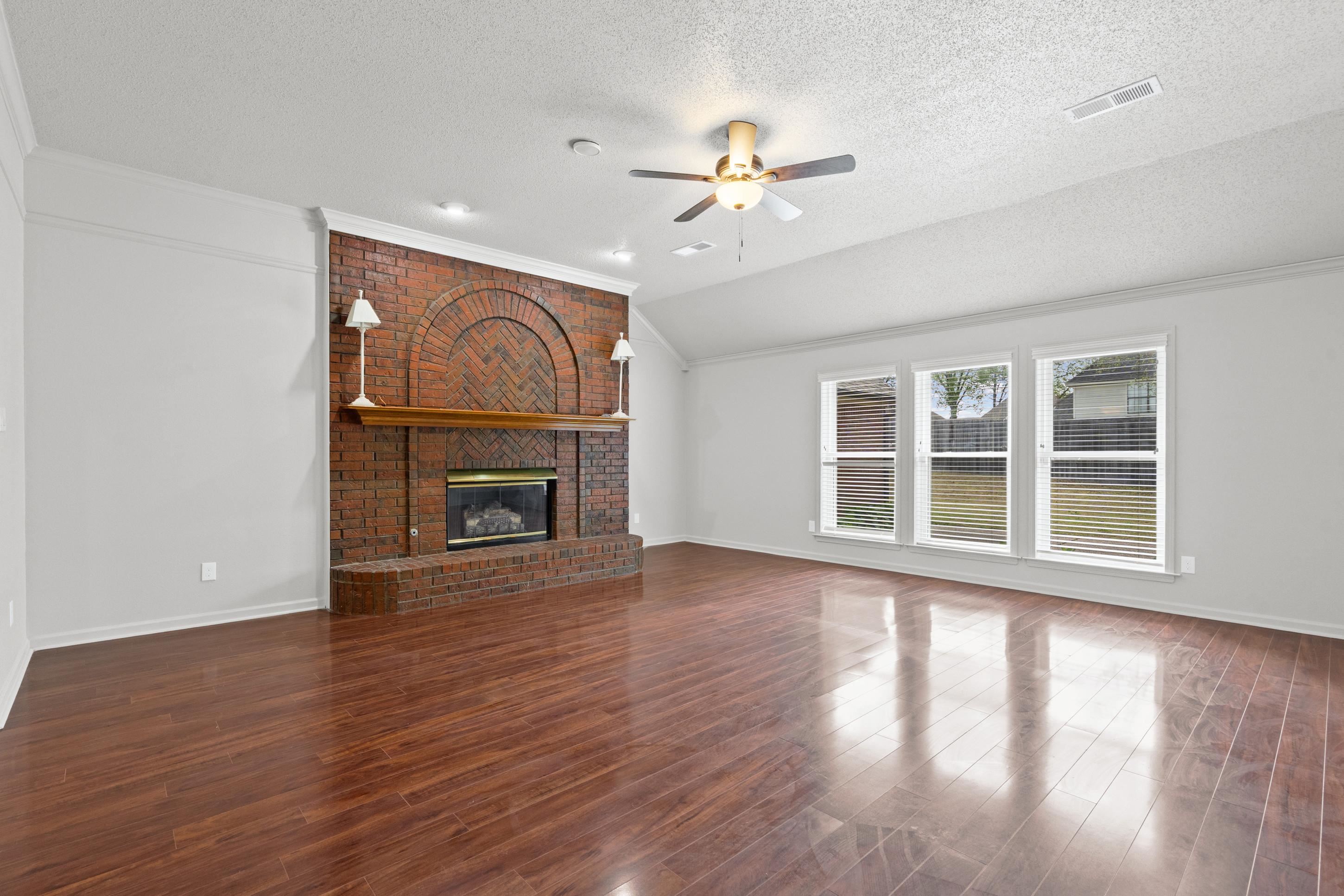 1301 Wolf Lair Drive Collierville, TN 38017 - Photo 9 of 32 Unfurnished living room with crown molding, a fireplace, ceiling fan, and dark wood-type flooring