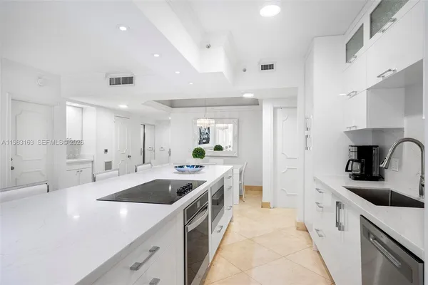 a large white kitchen with a sink and dishwasher