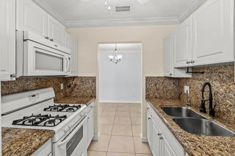 a kitchen with granite countertop a sink stove and cabinets