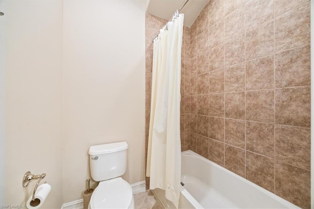 6504 Costa Circle Naples, FL 34113 - Photo 15 of 25 Bathroom featuring shower / tub combo with curtain, toilet, and baseboards