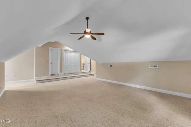 an empty room with chandelier fan and windows