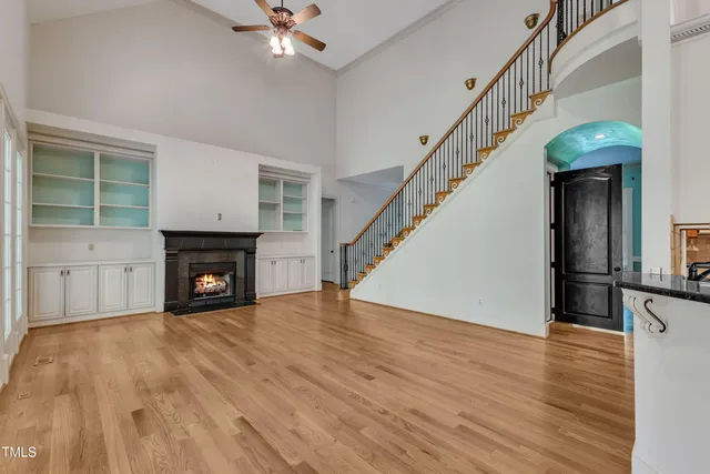 a view of an empty room with wooden floor fireplace and a window