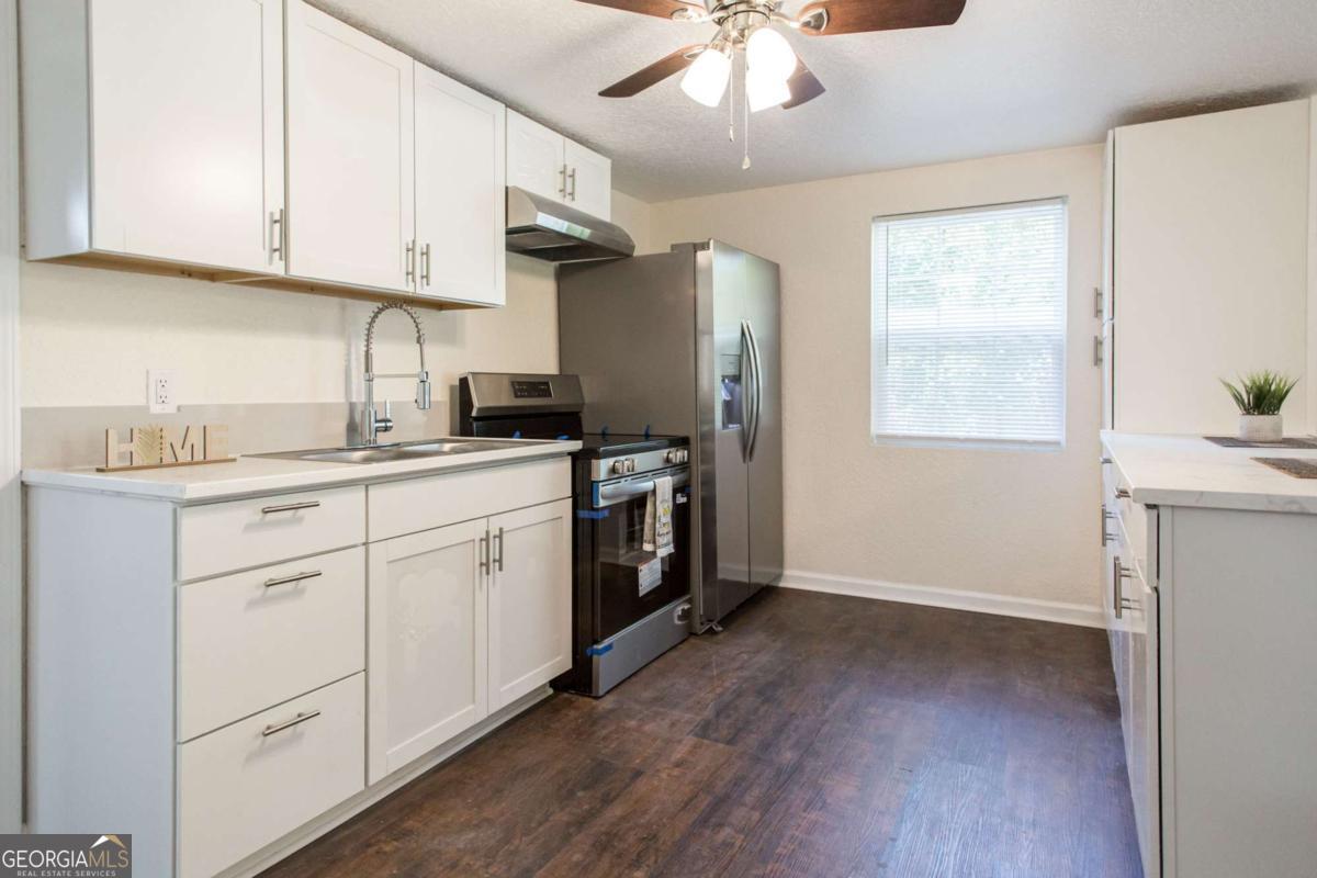 1410 Hazel Street Waycross, GA 31501 - Photo 8 of 21 a kitchen with a sink dishwasher and white cabinets with wooden floor